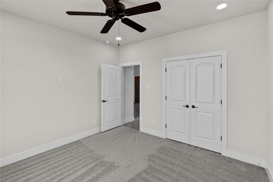 Unfurnished bedroom with ceiling fan, light colored carpet, and a closet