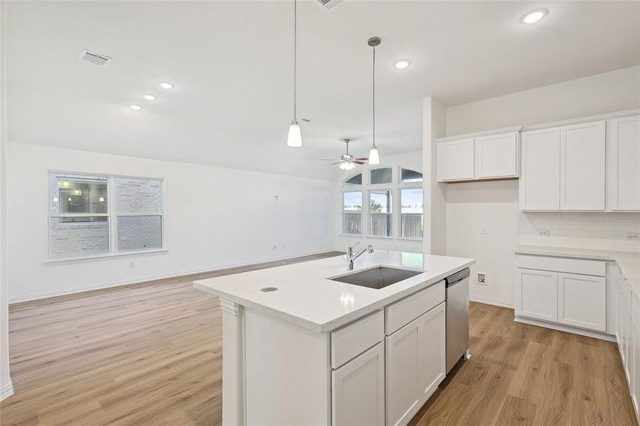 Kitchen with a kitchen island with sink, sink, white cabinets, ceiling fan, and stainless steel dishwasher