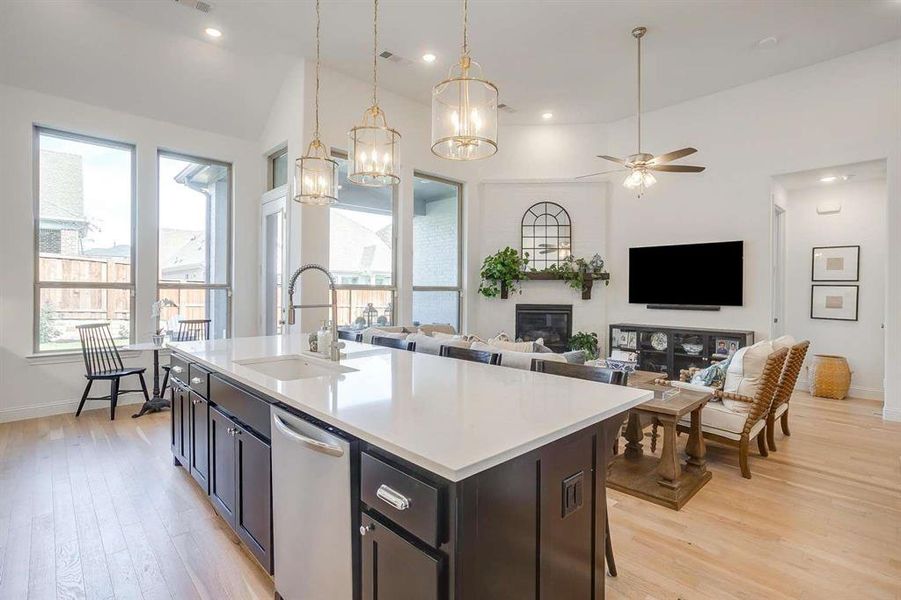 Kitchen with decorative light fixtures, an island with sink, light hardwood / wood-style floors, and sink