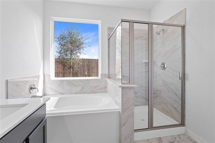 This primary bathroom is definitely move-in ready! Featuring an oversized framed walk-in shower with tile surround, separate garden tub for soaking after a long day with custom tile detailing, stained cabinets with light countertops, dual vanities, high ceilings, neutral paint, sleek and modern finishes.