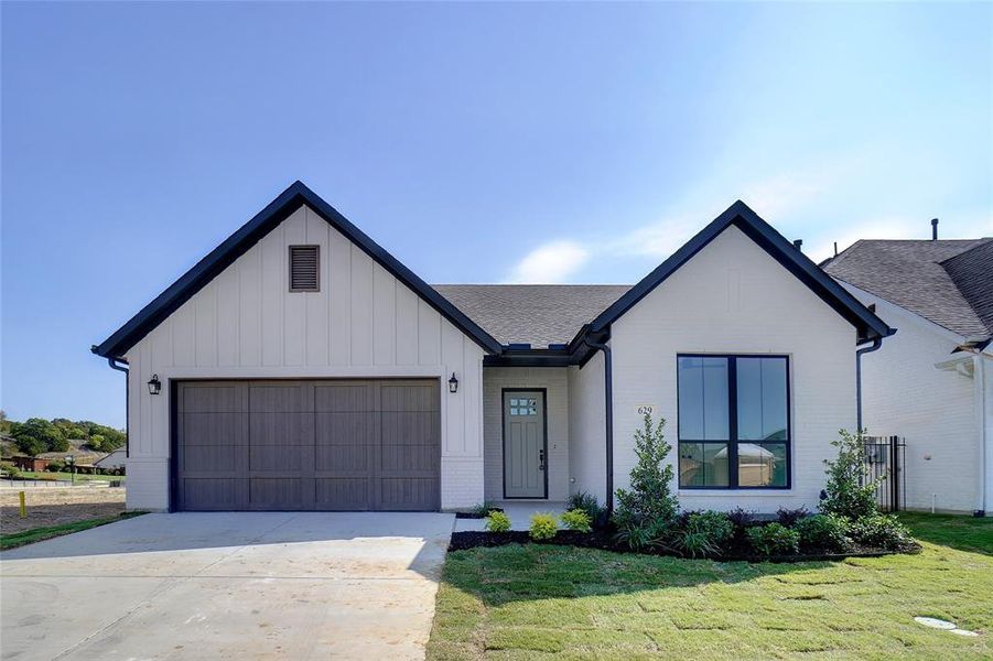 Modern farmhouse style home with a front yard and a garage