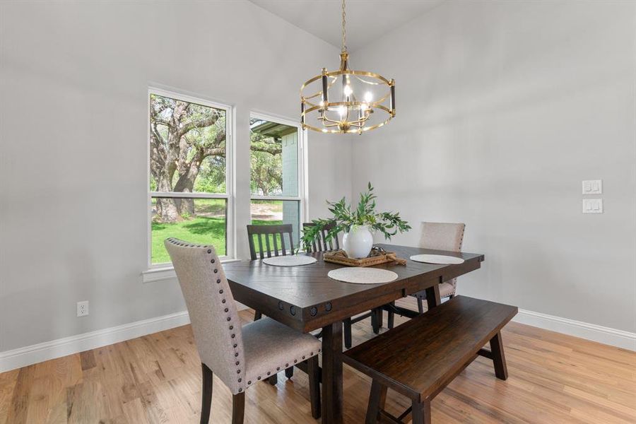 Dining area featuring high vaulted ceiling, an inviting chandelier, and light wood-type flooring