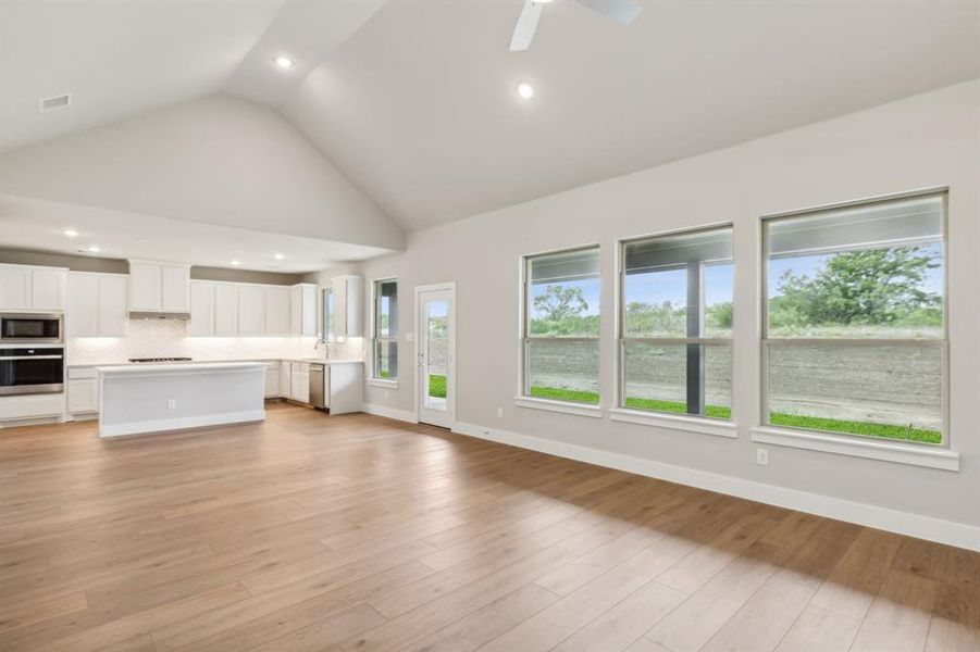 Unfurnished living room with ceiling fan, light hardwood / wood-style flooring, and high vaulted ceiling