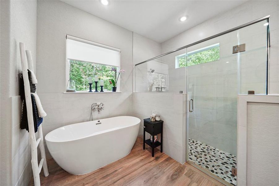 The owner's retreat offers a spa-like experience with a free-standing soaking tub and an oversized walk-in shower with frameless glass and river rock tile on the shower floor.