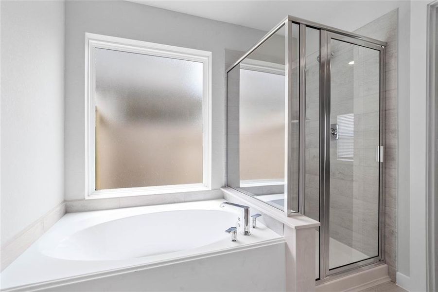 This primary bathroom is definitely move-in ready! Featuring dark framed walk-in shower with tile surround, separate garden tub for soaking after a long day with custom tile detailing, high ceilings, custom paint, sleek and dark modern finishes!