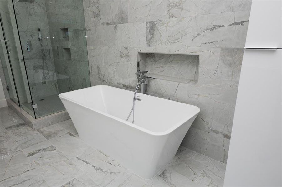 Bathroom with tile flooring, separate shower and tub, and tile walls