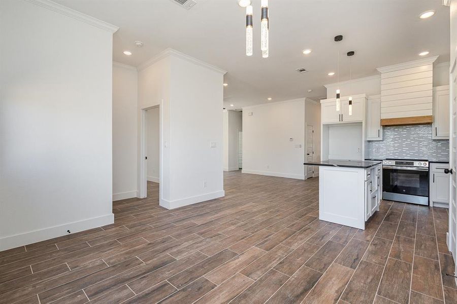 Kitchen featuring stainless steel range oven, white cabinetry, a kitchen island, decorative light fixtures, and dark hardwood / wood-style flooring