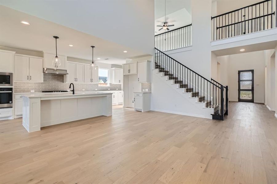 Kitchen featuring white cabinets, light hardwood / wood-style floors, stainless steel appliances, and a kitchen island with sink