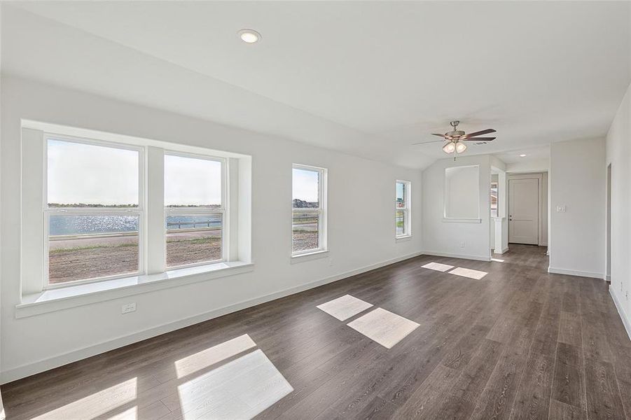 Unfurnished living room with dark wood-type flooring, ceiling fan, and a water view