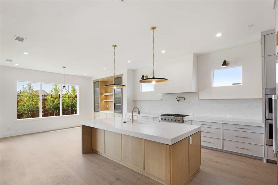 Kitchen featuring light hardwood / wood-style flooring, decorative light fixtures, and a spacious island