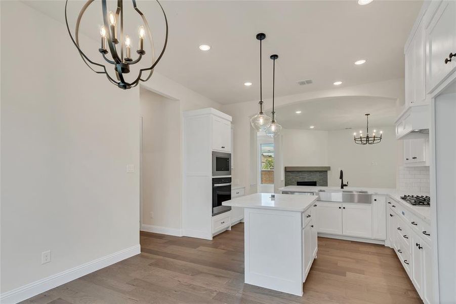 Kitchen featuring stainless steel appliances, kitchen peninsula, backsplash, light hardwood / wood-style floors, and a kitchen island