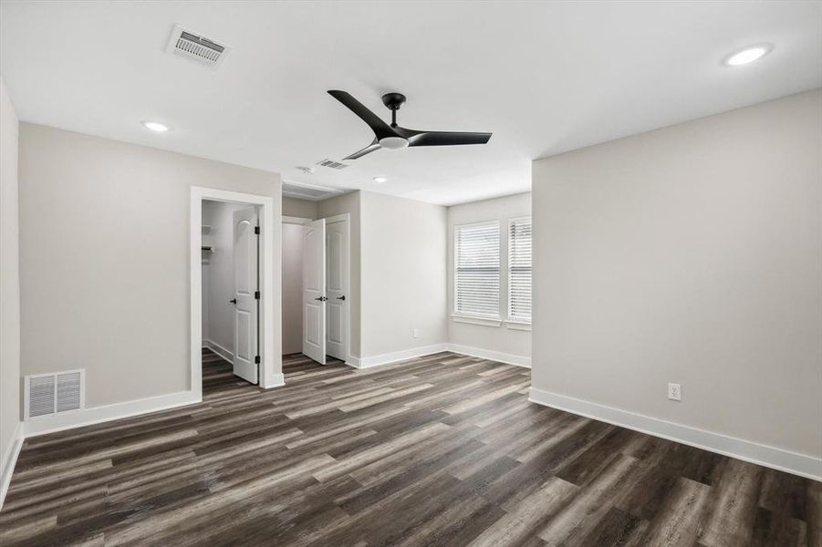 Unfurnished bedroom featuring dark hardwood / wood-style floors, ceiling fan, a walk in closet, and a closet