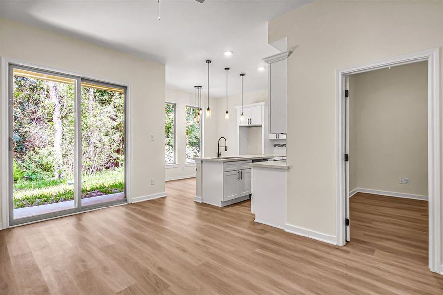 Open concept floor plan is bright and airy. The living room features a siding glass door overlooking the backyard; office and kitchen beyond.