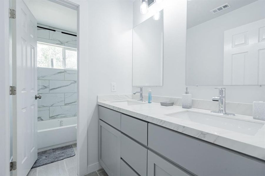 Bathroom with tiled shower / bath combo and vanity