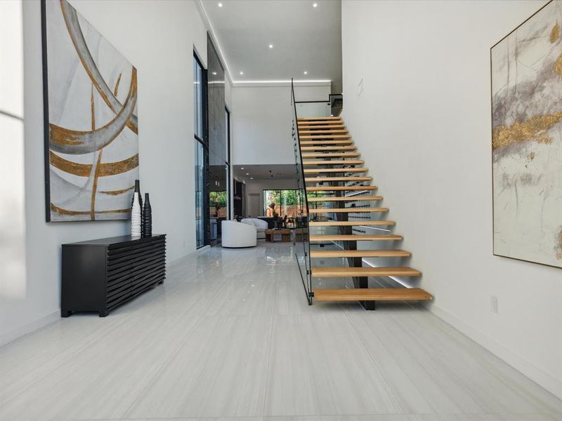 Floating stairs featuring a towering ceiling and tile flooring leading you into an open floor plan