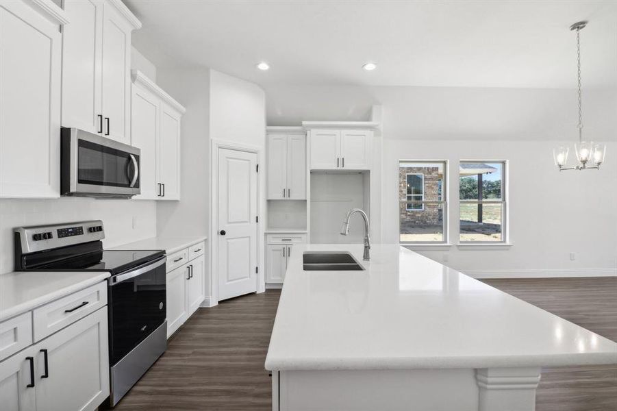 Kitchen featuring dark hardwood / wood-style floors, sink, an island with sink, white cabinetry, and stainless steel appliances