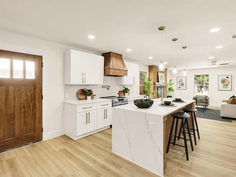 Kitchen featuring a center island with sink, custom exhaust hood, decorative light fixtures, and white cabinets