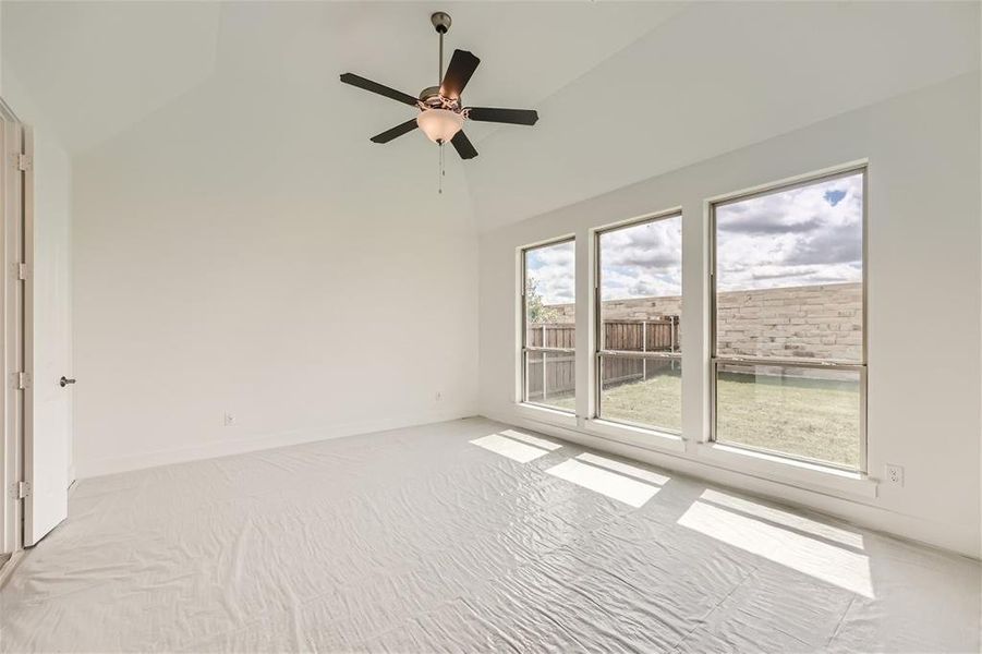 Carpeted empty room with high vaulted ceiling and ceiling fan