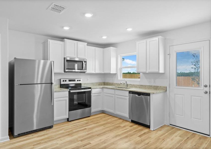 Stainless steel appliances, white cabinets and granite countertops are found in the kitchen