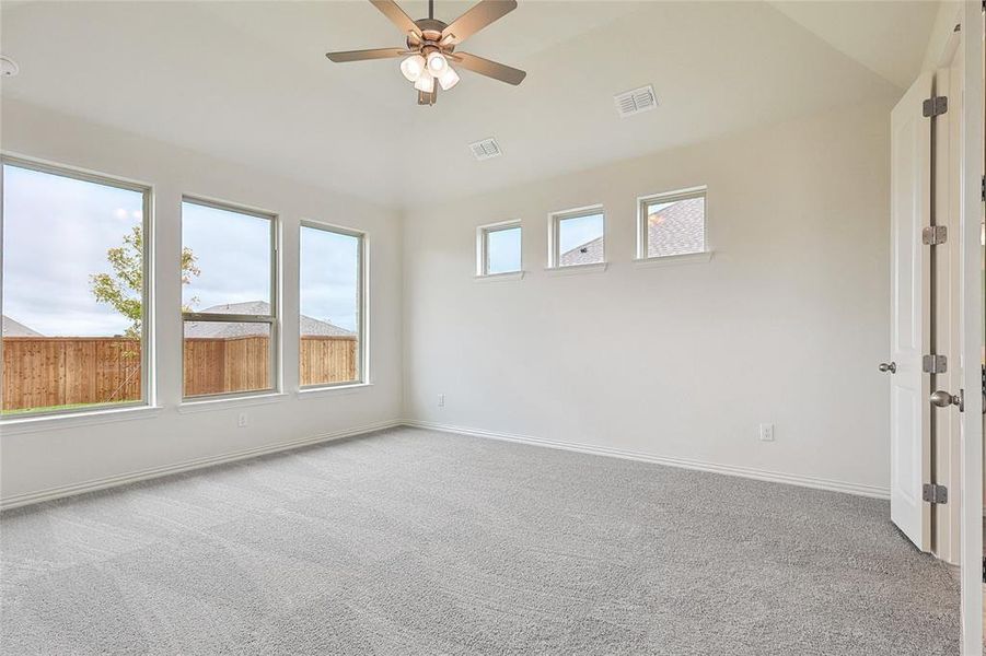 Carpeted empty room featuring ceiling fan and high vaulted ceiling