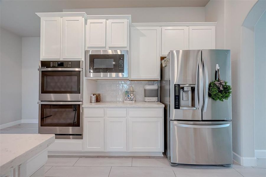 The kitchen features white cabinets,creating a clean and timelessaesthetic.