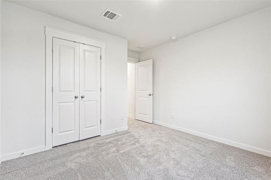 Unfurnished bedroom featuring light carpet and a closet