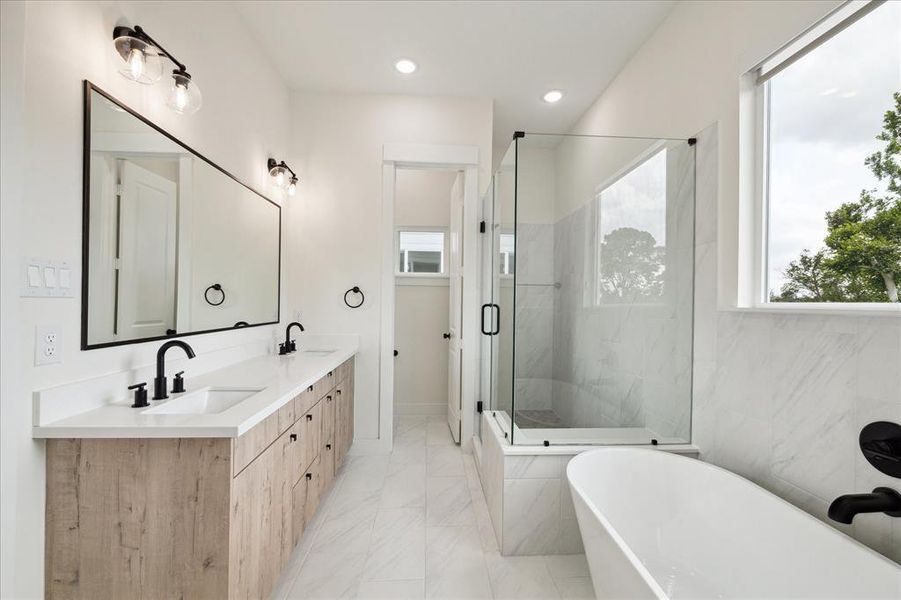 Luxurious primary bathroom with two vanities, ceramic tile floors, and tons of light.