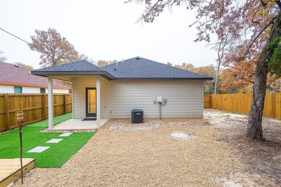 Rear view of house with cooling unit, a lawn, and a patio