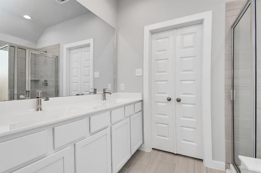 Elevate your daily routine at the elegant vanity, now equipped with double sinks, light countertops, modern hardware, and bright recessed lights. Sample photo of similar plan. As-built color and selections may vary.