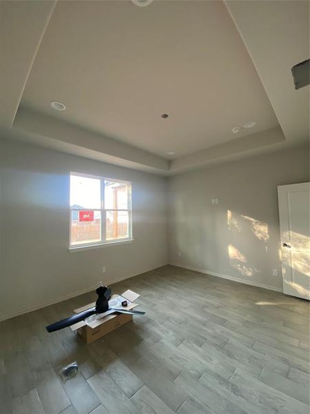 Unfurnished room with light wood-type flooring and a tray ceiling