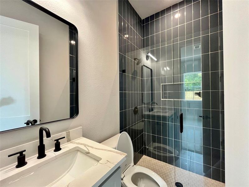 Bathroom featuring a tile shower, vanity, and toilet