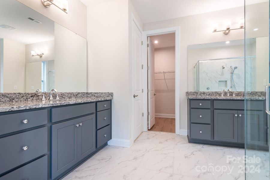 Dual vanities with upgraded cabinetry, granite counters, and gorgeous tile floors make this Primary ensuite bath feel like a Spa.
