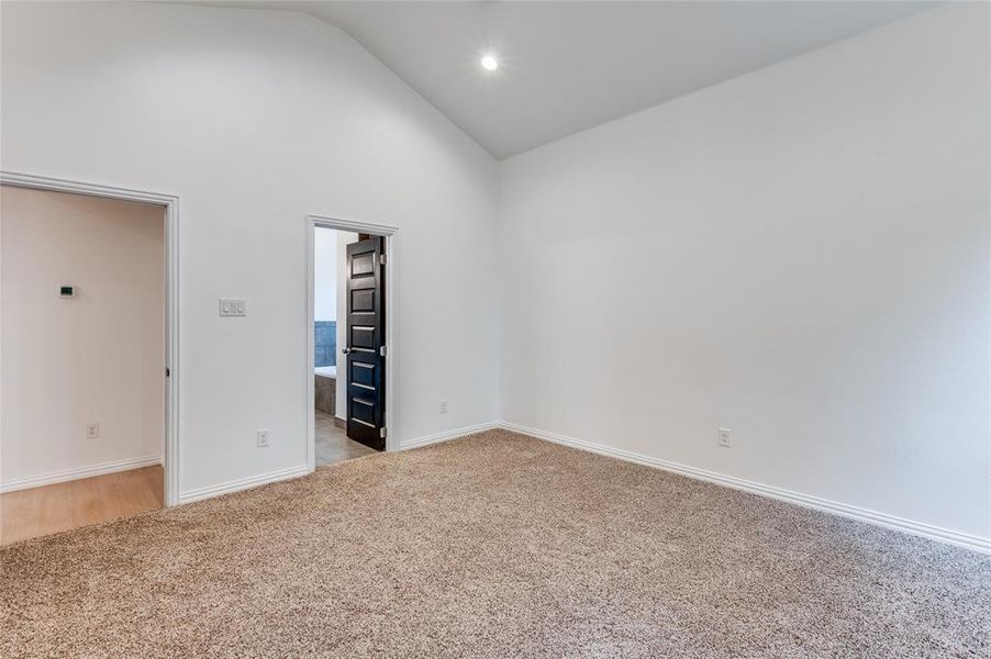 Carpeted empty room with high vaulted ceiling