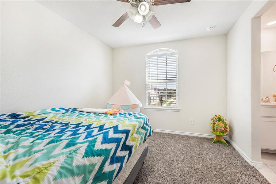 Carpeted bedroom with sink, ceiling fan, and ensuite bathroom