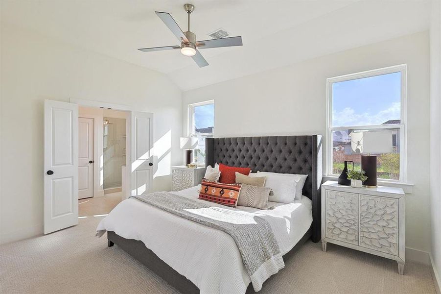 Bedroom with ceiling fan, multiple windows, light colored carpet, and ensuite bathroom