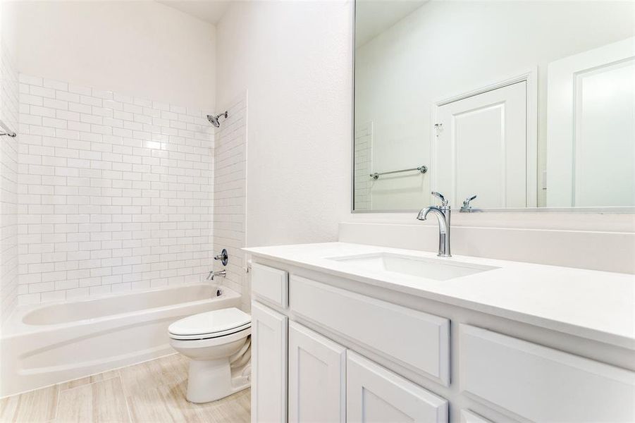 Full bathroom with large vanity, toilet, and tiled shower / bath combo