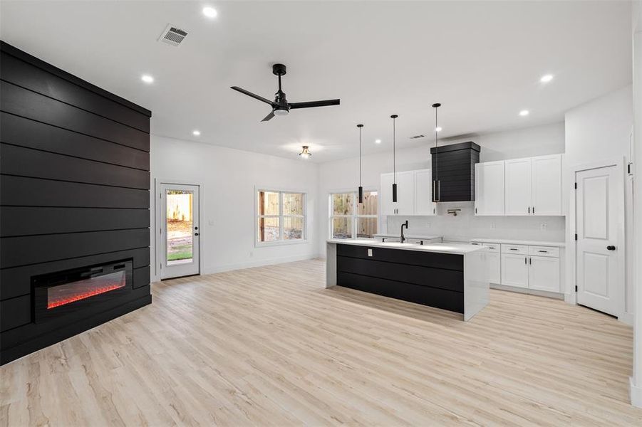 Kitchen featuring ceiling fan, a healthy amount of sunlight, an island with sink, and a large fireplace