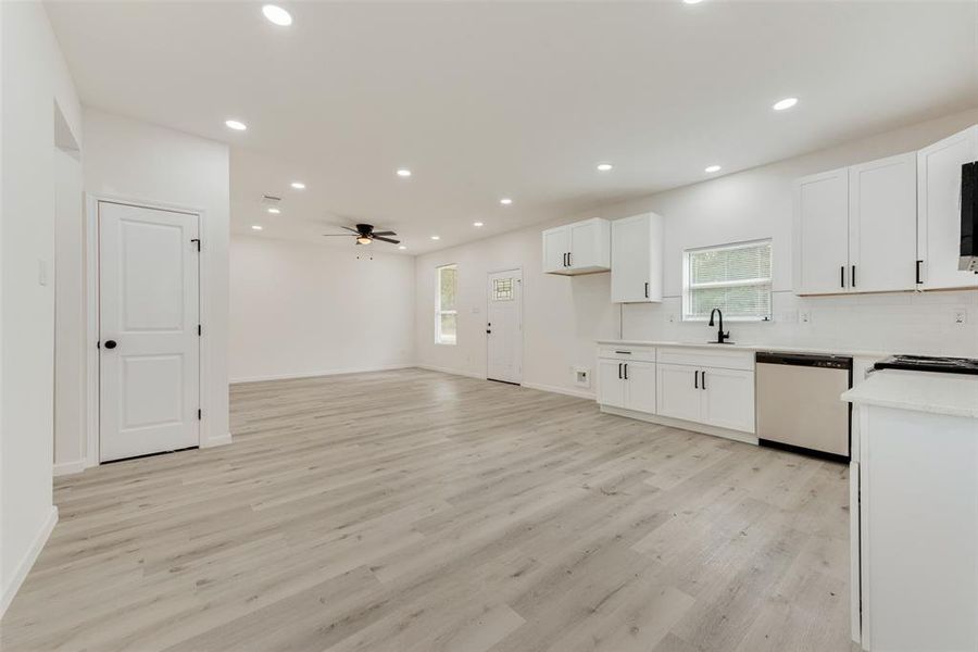 Kitchen with plenty of natural light, stainless steel dishwasher, ceiling fan, and light wood-type flooring