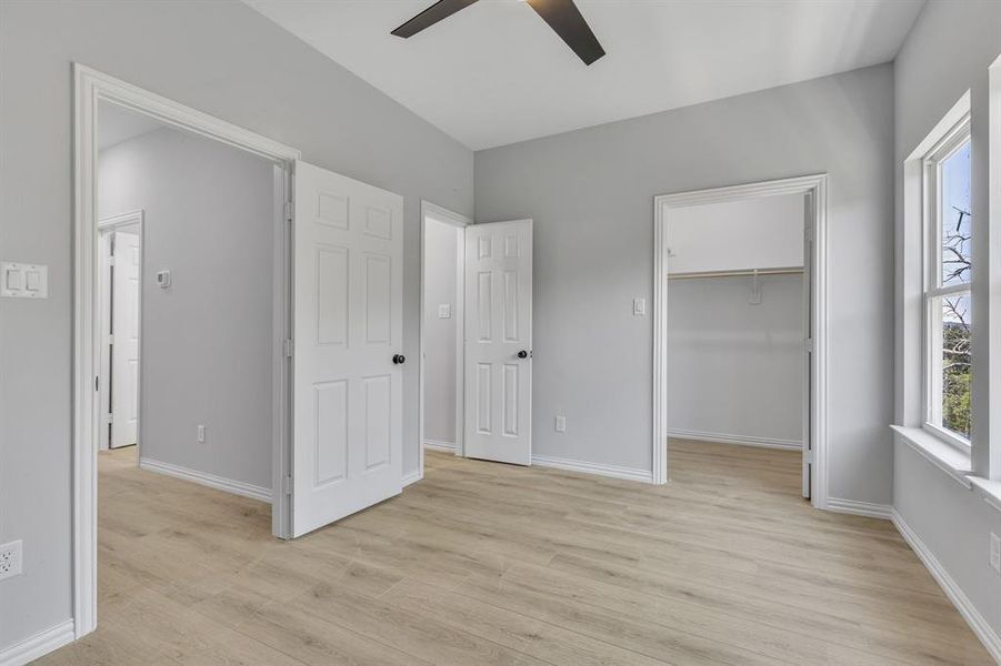 Unfurnished bedroom with ceiling fan, light hardwood / wood-style floors, a closet, and a walk in closet