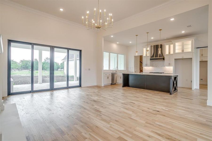 Kitchen with light hardwood / wood-style flooring, a kitchen island, custom exhaust hood, appliances with stainless steel finishes, and decorative backsplash