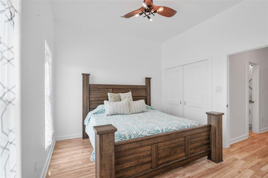 Another view of the primary bedroom with a ceiling fan, and built-in closet space.