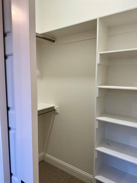 Walk in closet featuring dark colored carpet