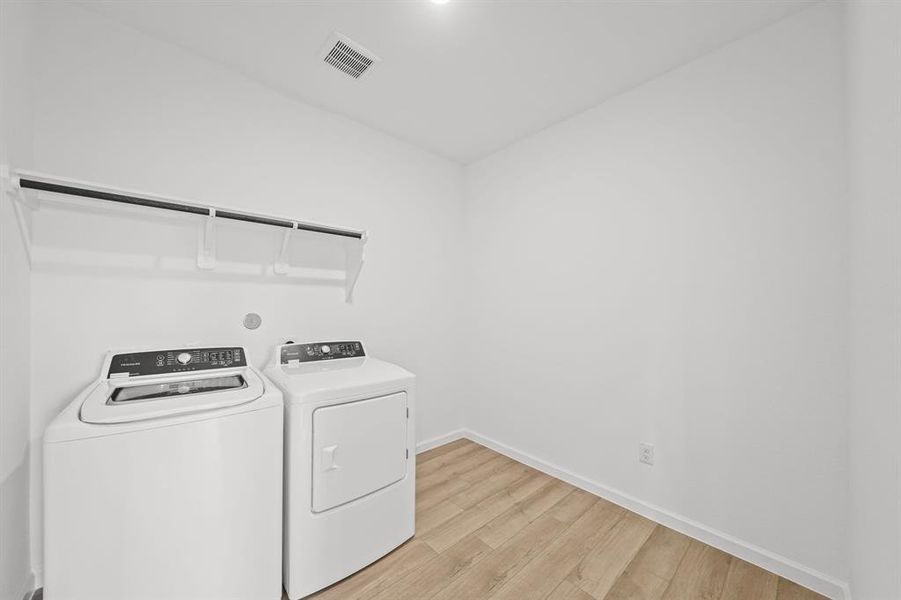 Laundry room featuring a top-loading washer and matching dryer, with a shelf above for storage.  Room to add a freezer