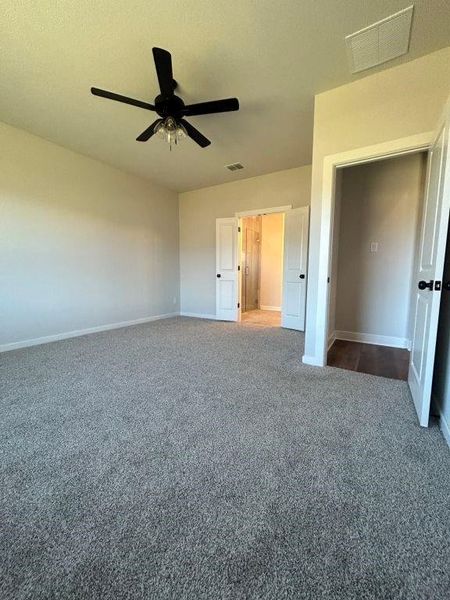 Unfurnished bedroom with dark colored carpet and ceiling fan