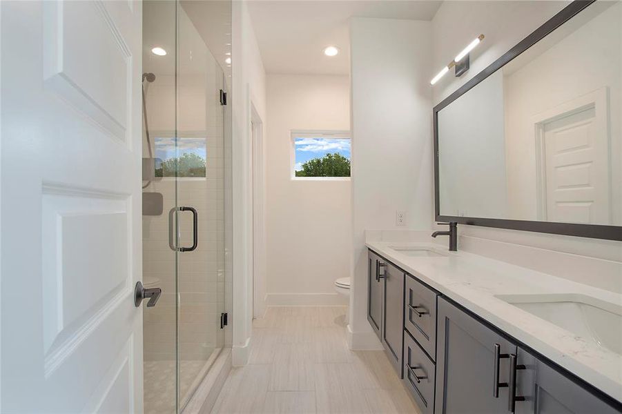 Bathroom featuring toilet, a shower with door, and vanity