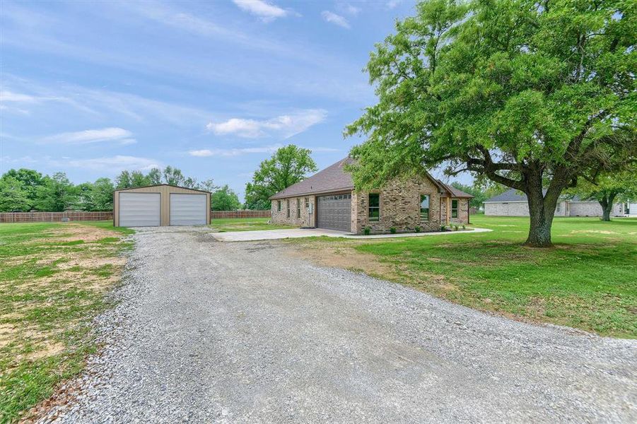 Single story home featuring a garage, an outbuilding, and a front yard