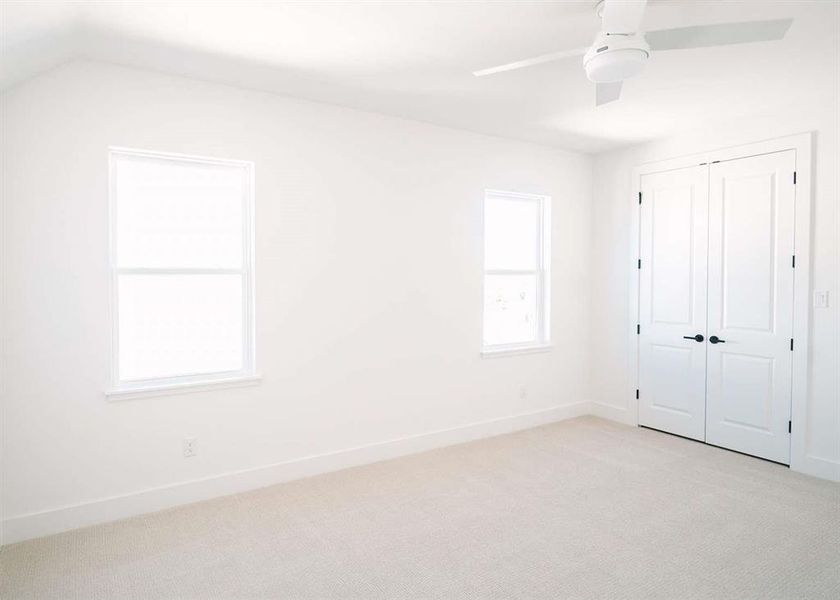 Unfurnished bedroom featuring lofted ceiling, light carpet, ceiling fan, and a closet