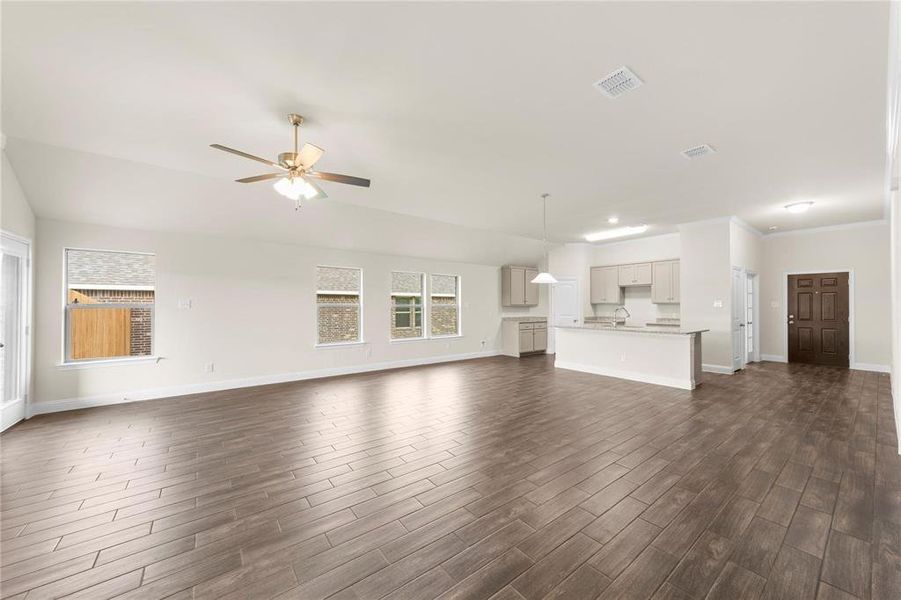 Unfurnished living room with ceiling fan, dark wood-type flooring, and sink