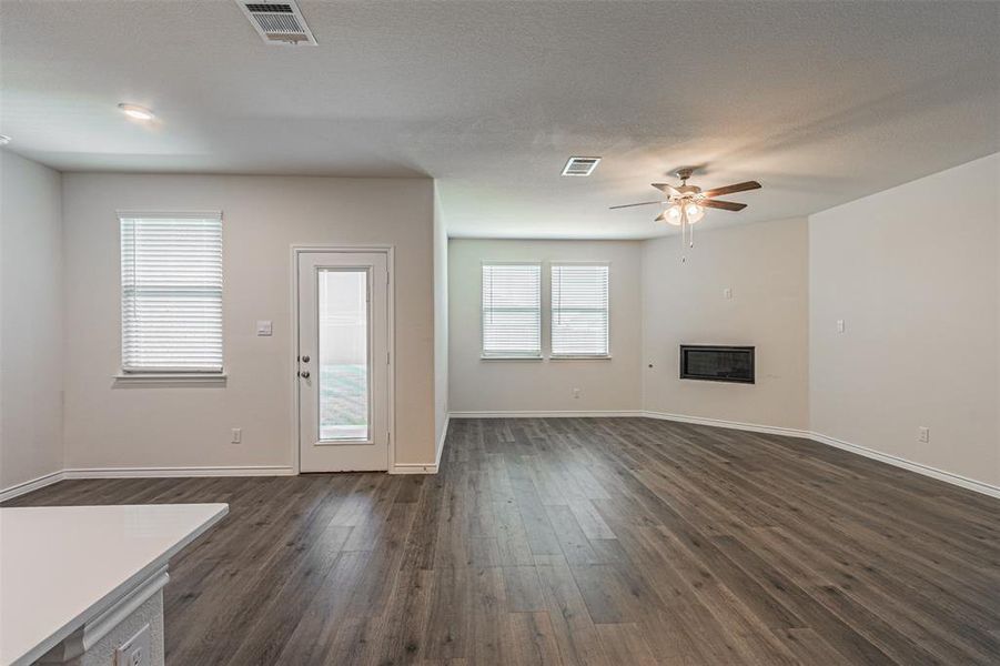 Unfurnished living room featuring dark hardwood / wood-style floors, ceiling fan, and a wealth of natural light