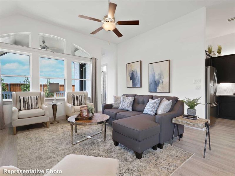 Living room featuring ceiling fan, light hardwood / wood-style flooring, and lofted ceiling